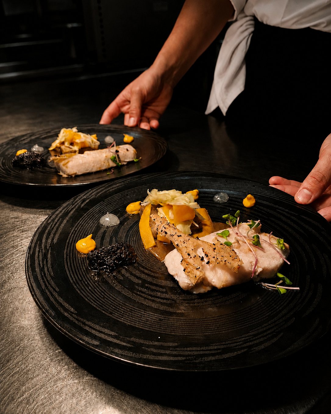Two plated dishes on the pass, ready to go out