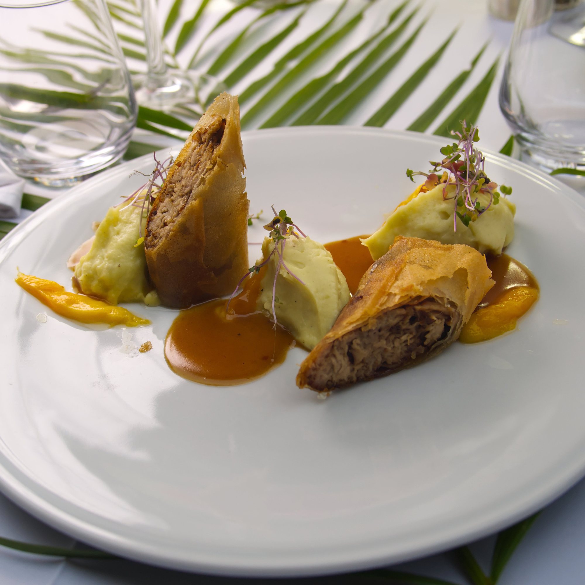 A plate by the Brigade, glasses and palm leaves on the tablecloth