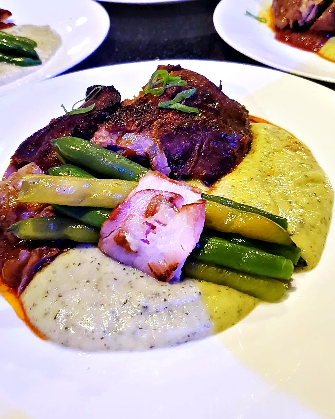Une assiette dressée à bord, légumes verts et sauce aux herbes