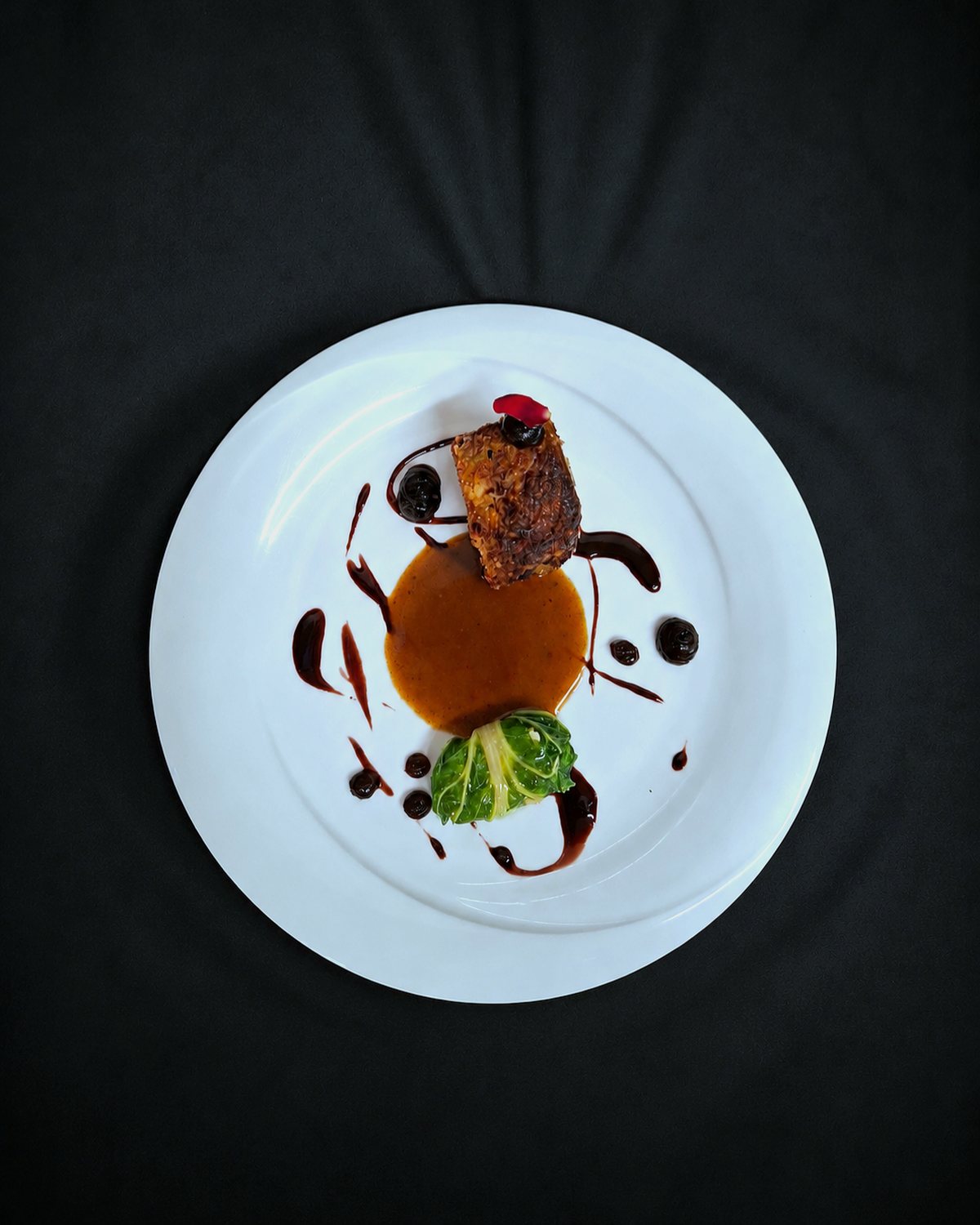 A plated dish seen from above, on a black cloth